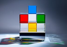 Auf dem quadratischen Edelstahlsockel liegen in einer Matrix angeordnete LEDs, deren dimmbares Licht sich von unten durch insgesamt 18 transparente und farbige Glaswürfel bricht.