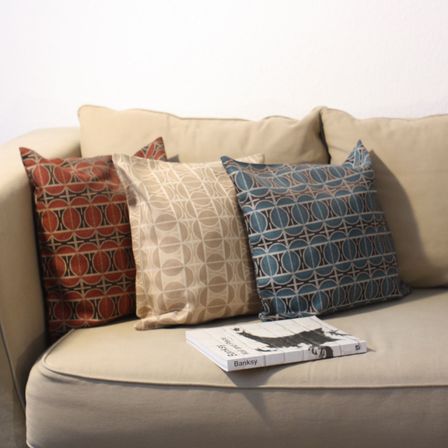 drei Kissen mit Mustern der Wiener Werkstätte auf einer Couch drapiert. 